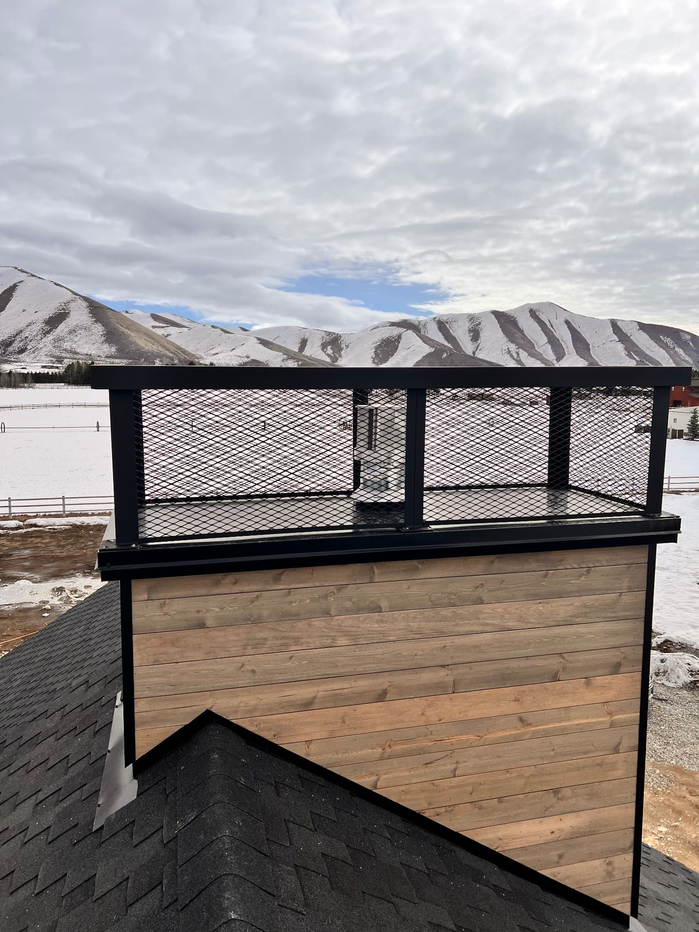 Black steel mesh rooftop guardrail overlooking snow-covered mountains near Ketchum, Idaho