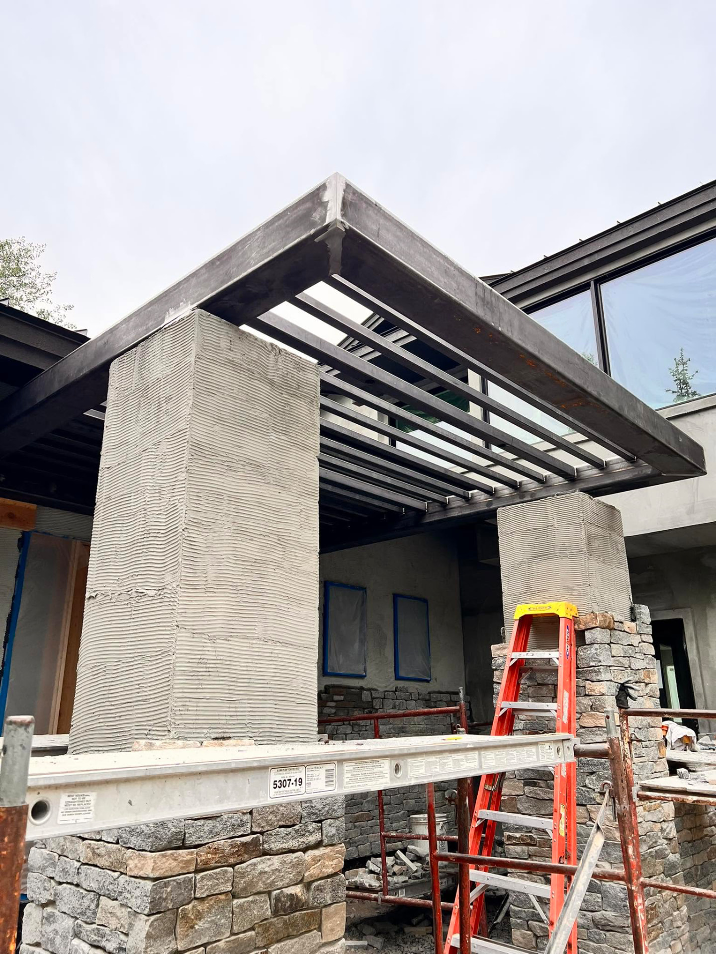 Steel pergola and stone columns on a modern residential build under construction