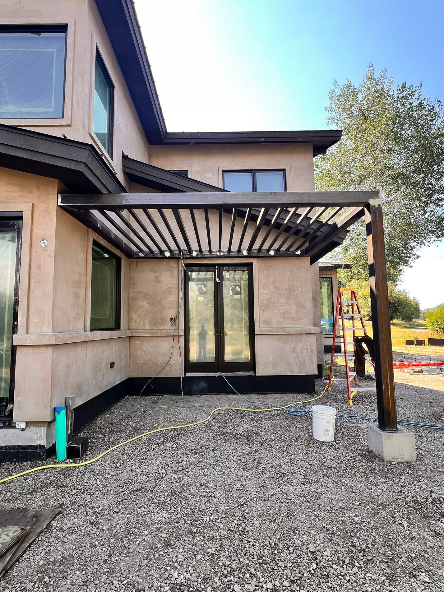 Dark bronze steel pergola with slatted roof built over a modern home patio in Ketchum, Idaho